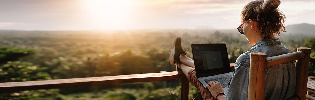 person sitting on vacation rental deck with computer